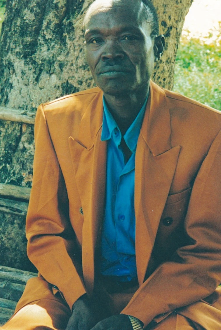 Belay Makonnen sits for a portrait beside a large tree
