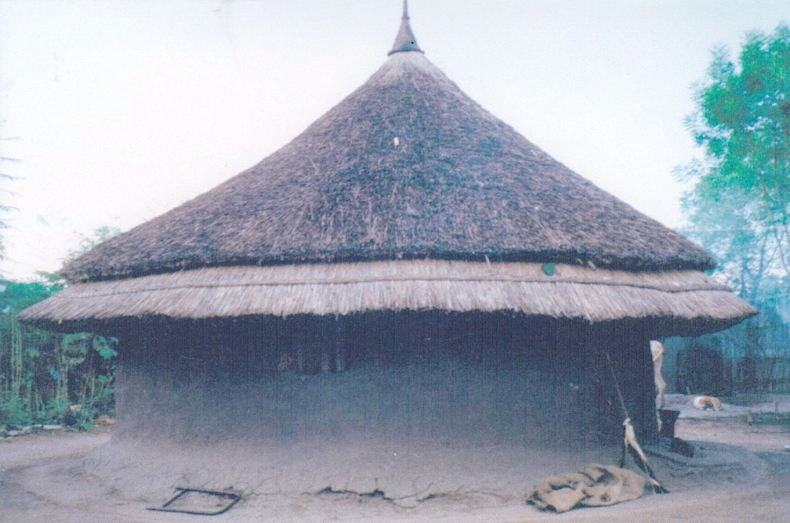 A circular Nuer house with mud-plastered walls and a steep thatched roof in Gambela