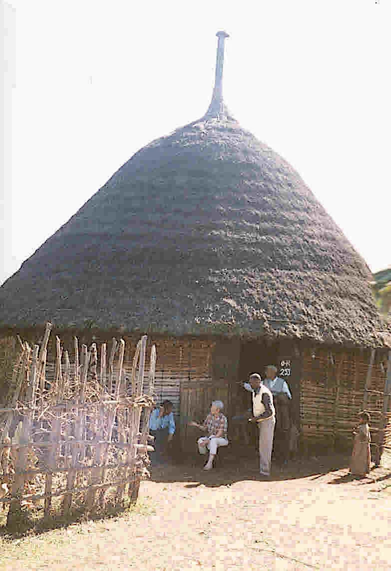 A storytelling session outside a large round Gurage house with a steep thatched roof