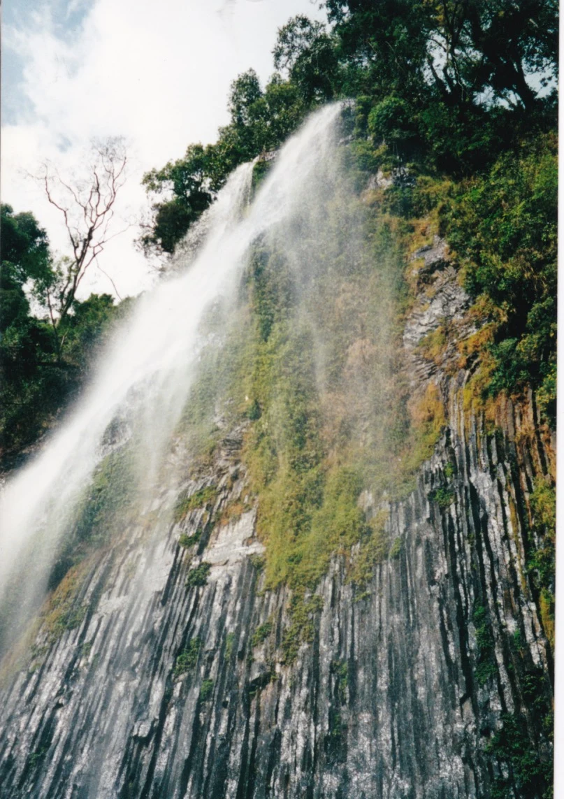 Berta Falls descending over a high rock face in the forest near Bonga