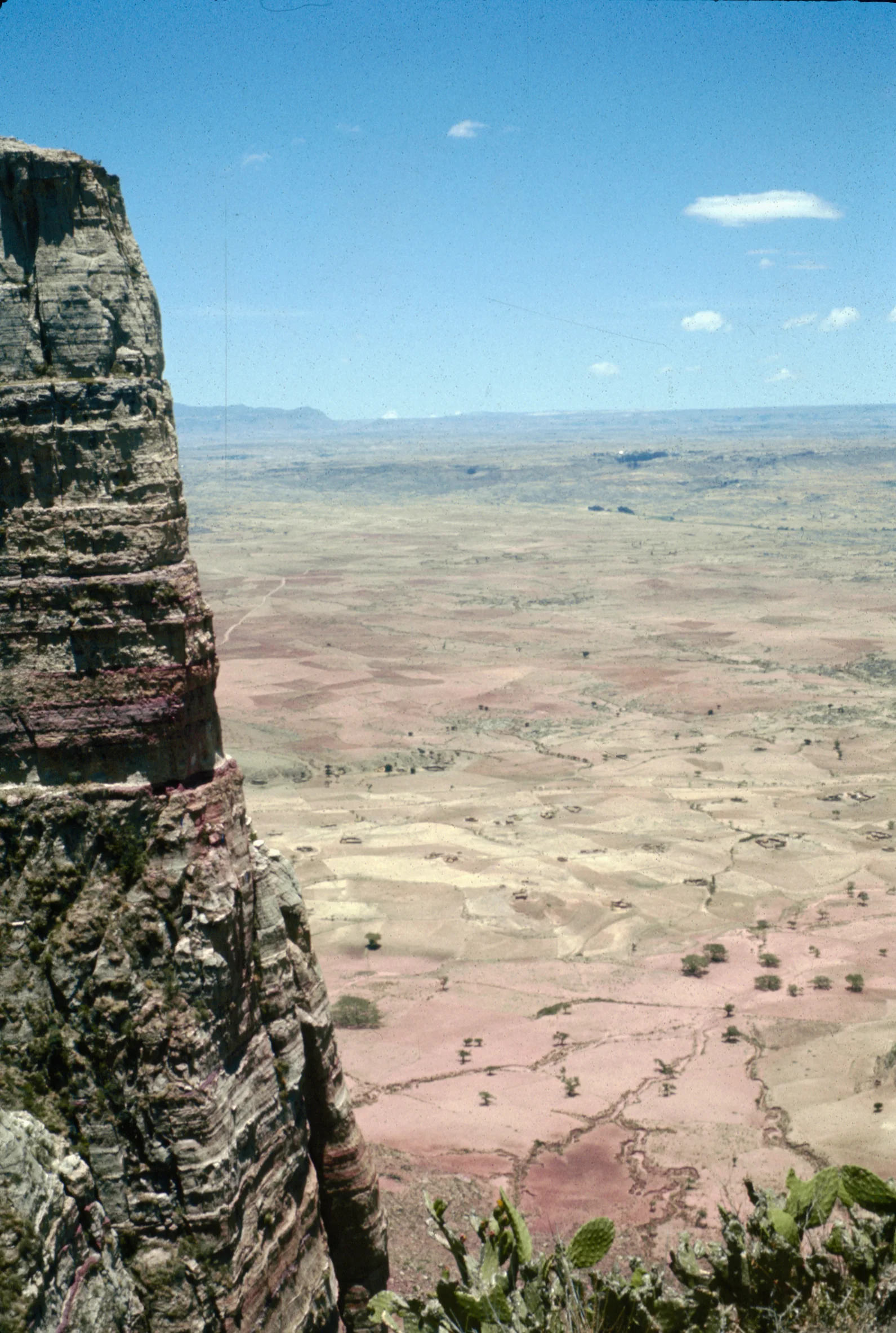 A narrow path beside a high rock face leading towards a church in Tigray